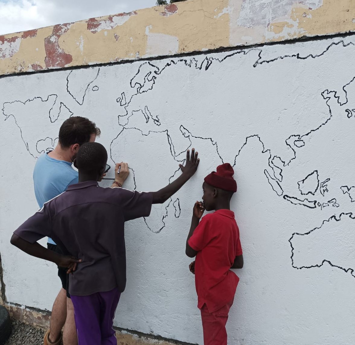 Kinder malen eine Weltkarte auf die Wand