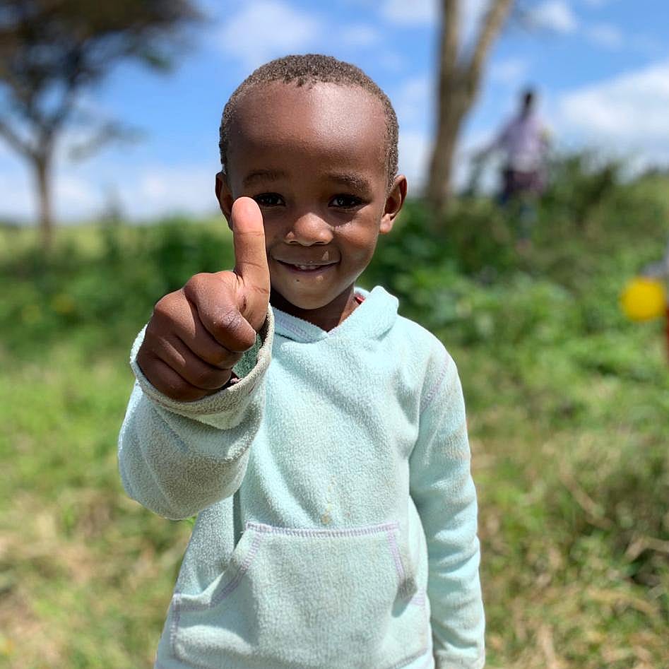 Ein Kind unseres Waisenhauses in Kenia zeigt den Daumen hoch für das Engagement von Unternehmen